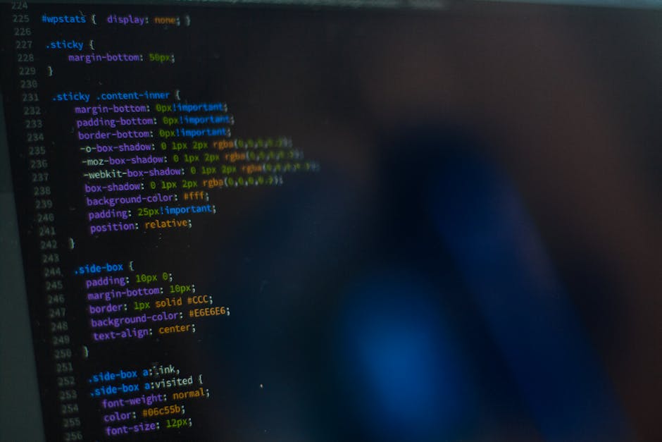 A screenshot of a computer screen displaying lines of code in various colors, including green, yellow, blue, and purple, on a dark background. The code appears to be related to web design or developme